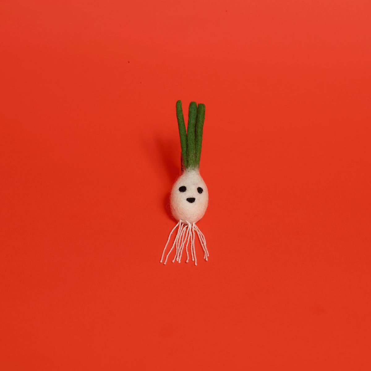 Ware of the Dog felted wool onion cat toy with strings on bottom on red background