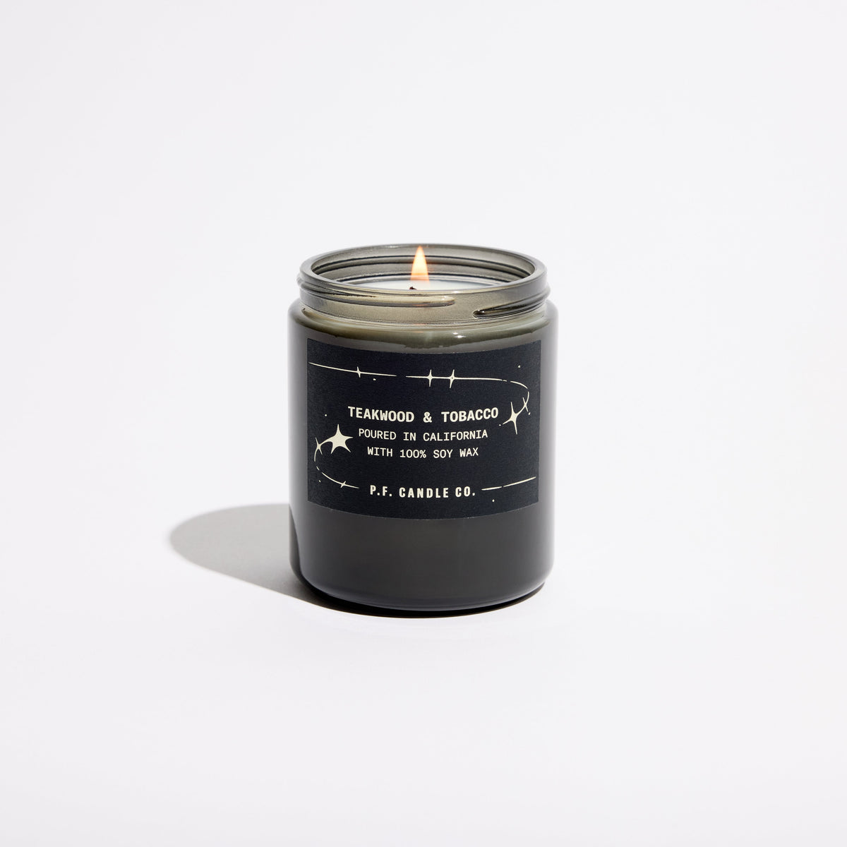 P.F. Candle Co. Celestial Collection Candle in Teakwood & Tobacco, smoky grey glass jar with black lid