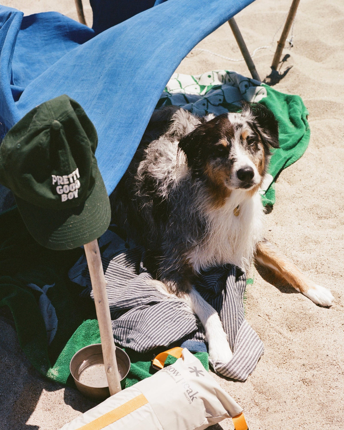 Aussie on the beach next to a dark green Pretty Good Boy hat