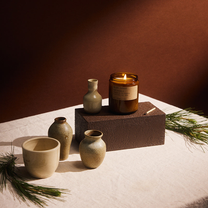 P.F. Candle Co. Standard Candle in Spruce styled with ceramics and evergreen sprigs